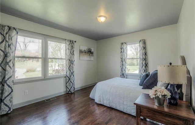 bedroom with visible vents, wood finished floors, and baseboards