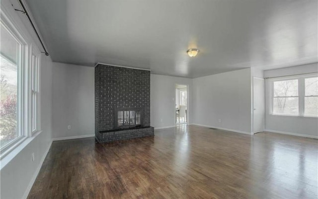 unfurnished living room with a brick fireplace, baseboards, and wood finished floors