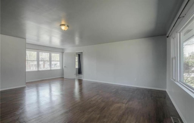 unfurnished room with visible vents, baseboards, and dark wood-type flooring