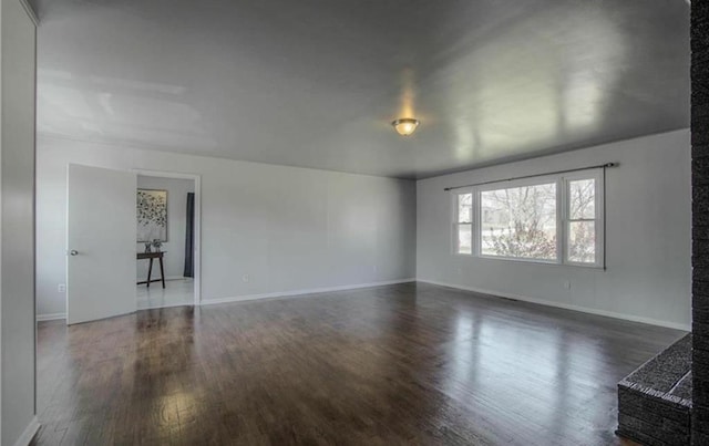 empty room featuring dark wood-style floors and baseboards