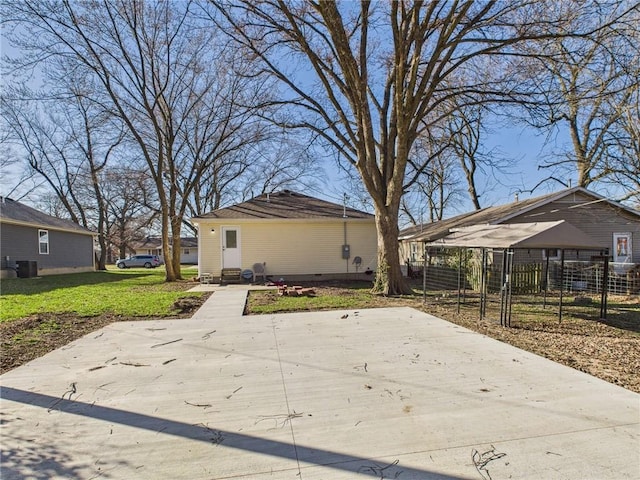 back of house with fence, a lawn, and central AC