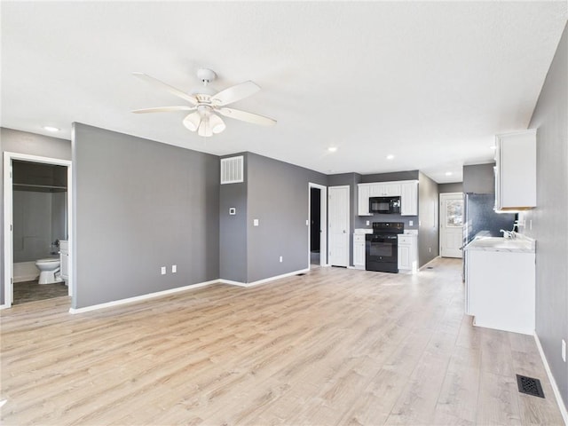 unfurnished living room featuring baseboards, visible vents, light wood finished floors, and ceiling fan