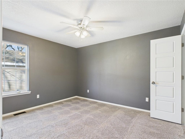 carpeted spare room featuring visible vents, a textured ceiling, baseboards, and ceiling fan