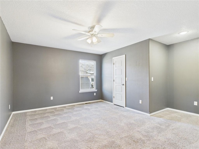 carpeted spare room with baseboards, a textured ceiling, and ceiling fan