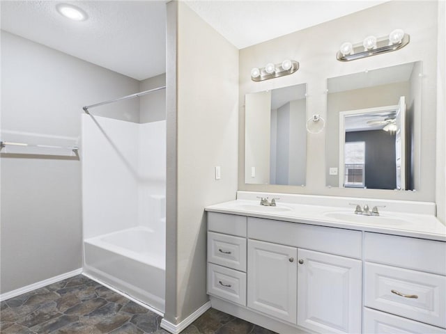 bathroom featuring double vanity, tub / shower combination, baseboards, and a sink