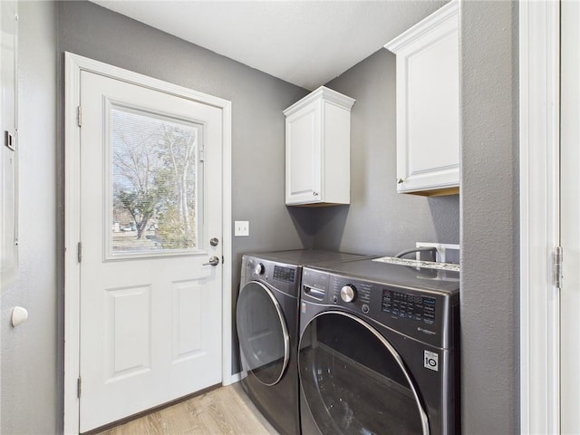 washroom with washer and dryer, cabinet space, and light wood-style flooring