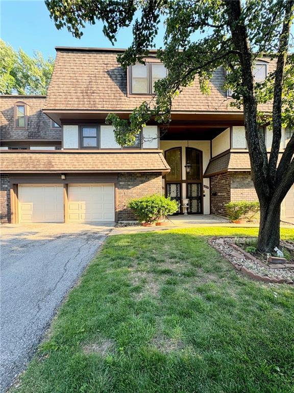 view of front of house featuring a front yard, brick siding, a garage, and driveway