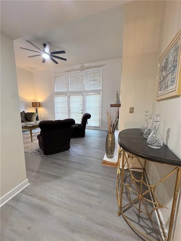 living area with ceiling fan, baseboards, and wood finished floors