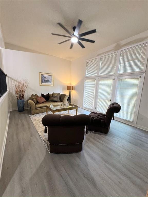 living area with ceiling fan, baseboards, and wood finished floors