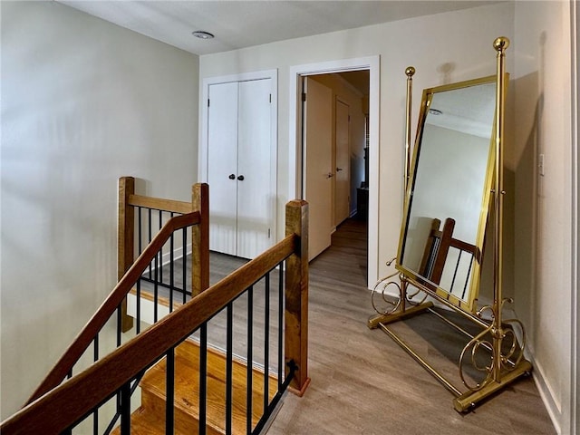 hallway with an upstairs landing and wood finished floors