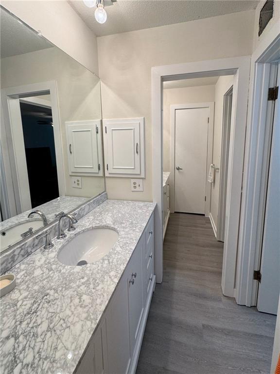 bathroom with a textured ceiling, wood finished floors, and vanity