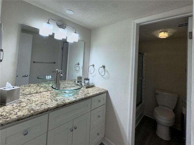 full bathroom featuring vanity, visible vents, a shower with shower door, a textured ceiling, and toilet