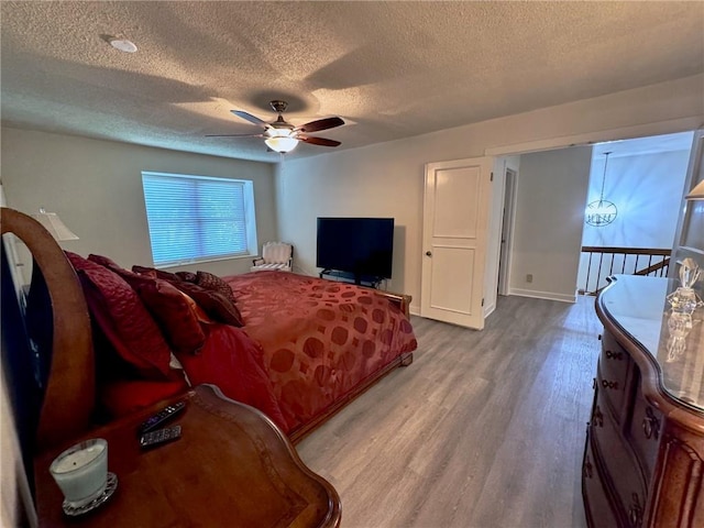 bedroom featuring a textured ceiling, wood finished floors, baseboards, and ceiling fan