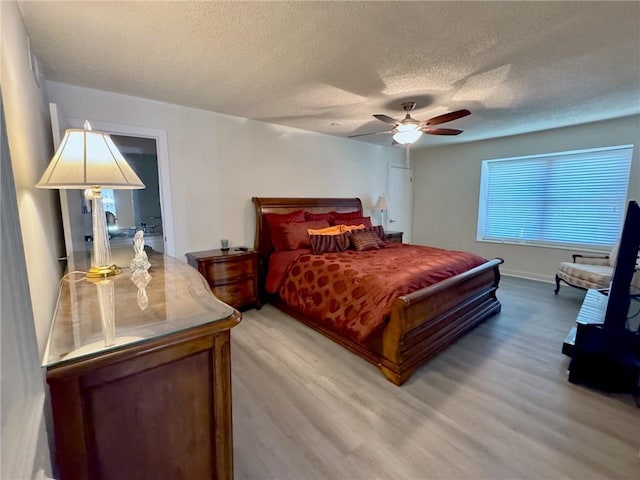 bedroom with ceiling fan, light wood-type flooring, and a textured ceiling