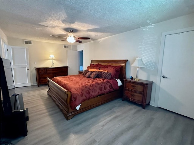 bedroom with wood finished floors, visible vents, and a textured ceiling