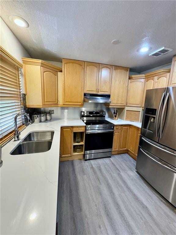 kitchen with visible vents, under cabinet range hood, light wood-type flooring, appliances with stainless steel finishes, and a sink