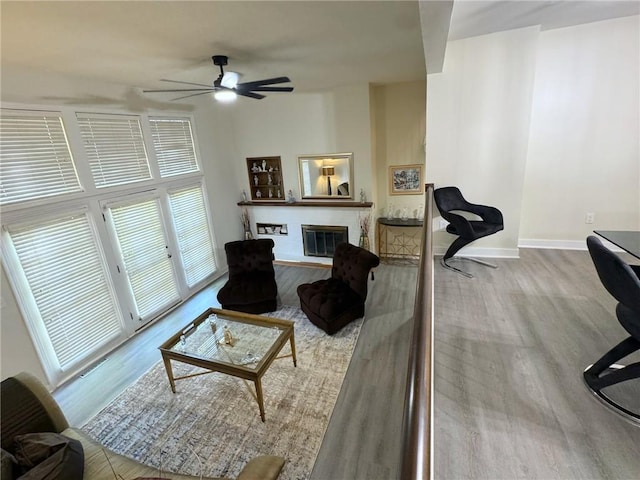 living area with a glass covered fireplace, baseboards, and wood finished floors