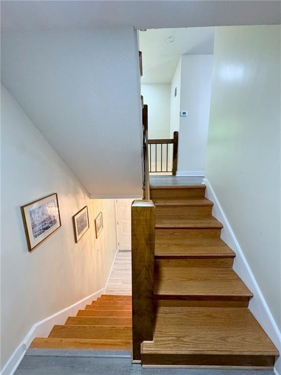 staircase featuring baseboards and wood finished floors