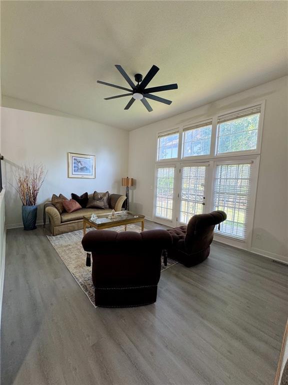 living area featuring wood finished floors, baseboards, and ceiling fan