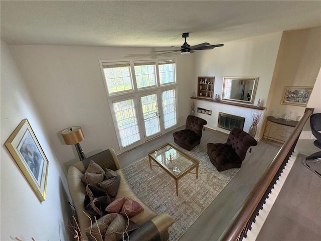 living room featuring a glass covered fireplace and ceiling fan