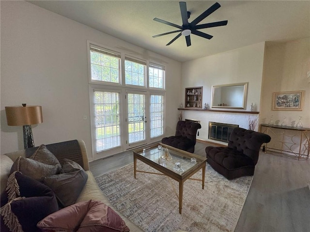 living area featuring visible vents, a fireplace, ceiling fan, and wood finished floors