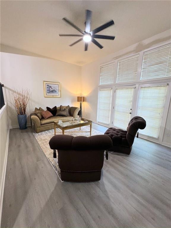 living area featuring wood finished floors, baseboards, and ceiling fan