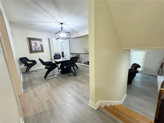 dining area with baseboards, an inviting chandelier, and wood finished floors