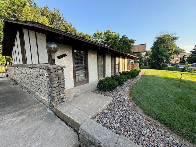 view of side of home featuring stucco siding and a yard