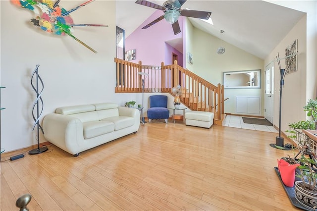 living area featuring ceiling fan, stairway, high vaulted ceiling, and wood finished floors