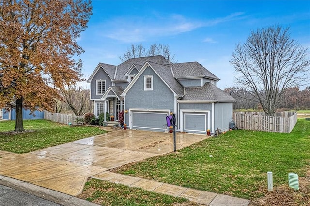 traditional-style home with fence, an attached garage, a shingled roof, a front lawn, and concrete driveway