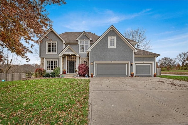 traditional-style home with fence, an attached garage, stucco siding, a front lawn, and concrete driveway