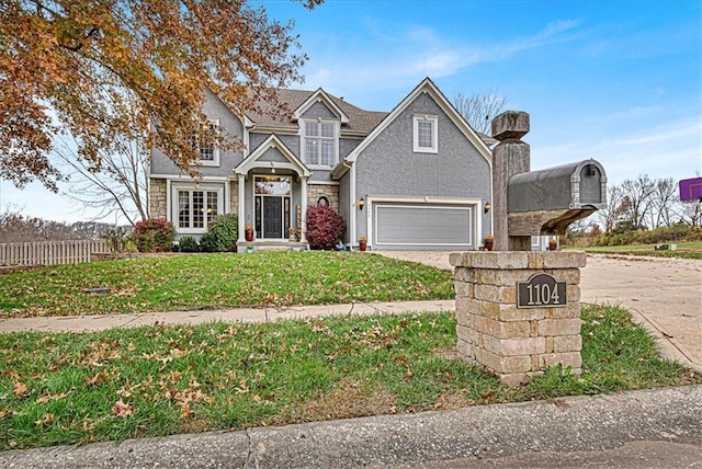 traditional home with fence, concrete driveway, a front yard, a garage, and stone siding