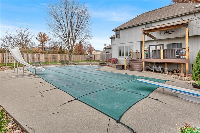 view of swimming pool with a deck, a fenced backyard, a fenced in pool, and a water slide