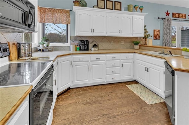 kitchen with electric stove, backsplash, wood finished floors, black microwave, and light countertops