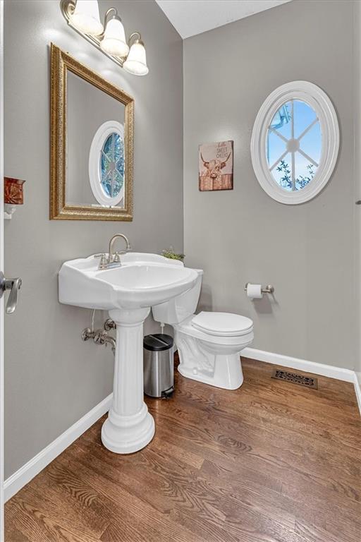 bathroom featuring visible vents, toilet, wood finished floors, and baseboards