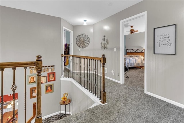 hall featuring carpet, an upstairs landing, and baseboards