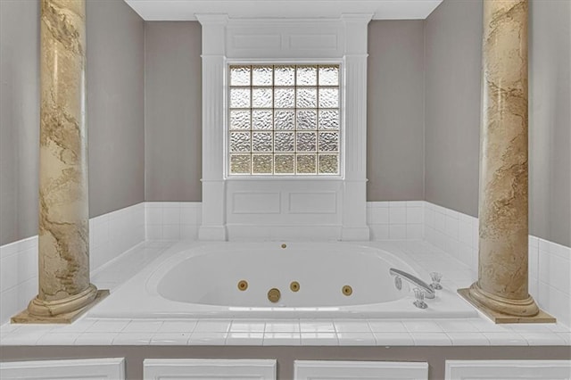 full bath featuring decorative columns and a whirlpool tub