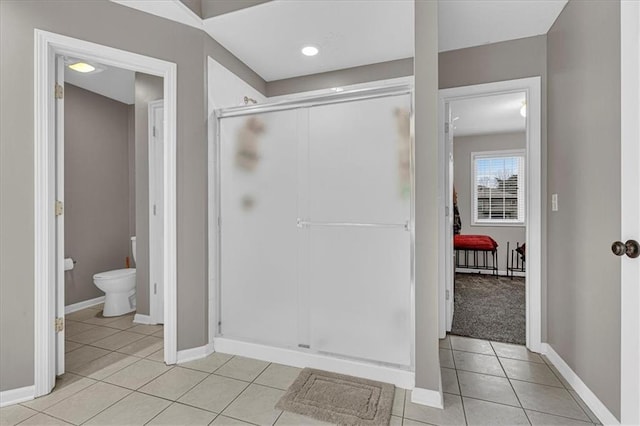 bathroom featuring tile patterned flooring, a shower stall, toilet, and baseboards