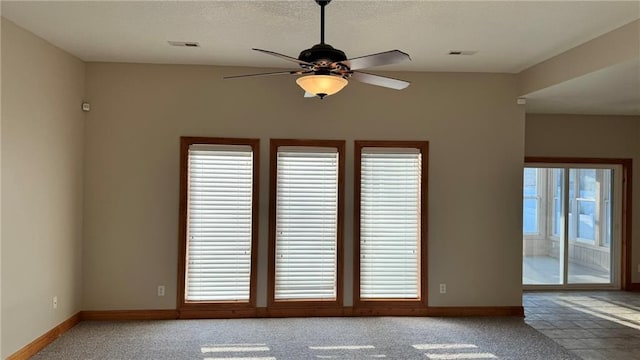 carpeted empty room featuring visible vents, a textured ceiling, baseboards, and a ceiling fan