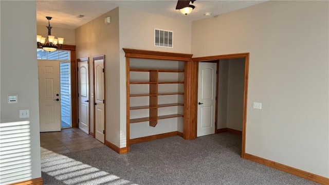 foyer entrance with a chandelier, visible vents, baseboards, and carpet floors