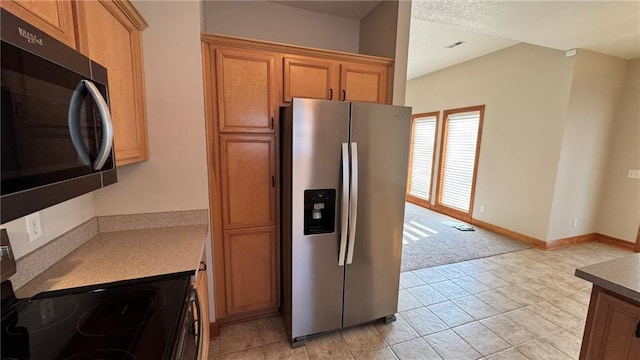 kitchen featuring brown cabinetry, electric range, stainless steel fridge, and baseboards