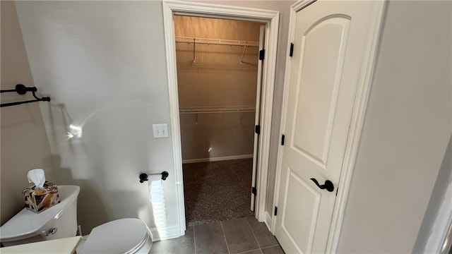 bathroom featuring baseboards, toilet, and a spacious closet