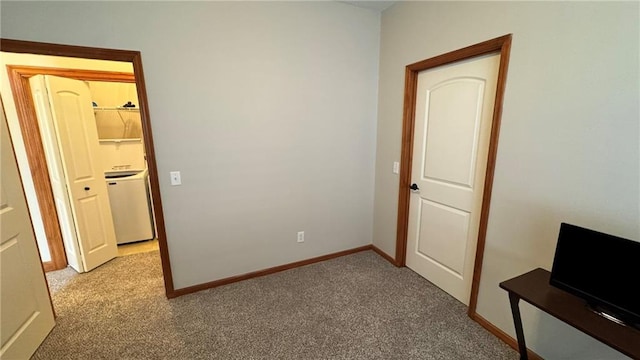 unfurnished bedroom featuring washer / dryer, light colored carpet, and baseboards