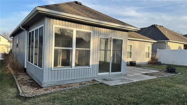 back of house with a patio area, a lawn, a shingled roof, and fence