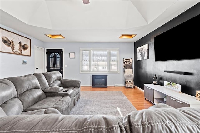 living room featuring a raised ceiling, light wood-style floors, attic access, and a fireplace