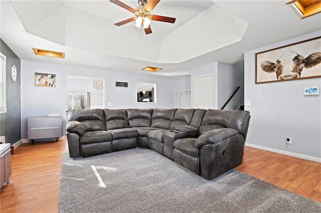 living room with attic access, light wood-style floors, and a tray ceiling