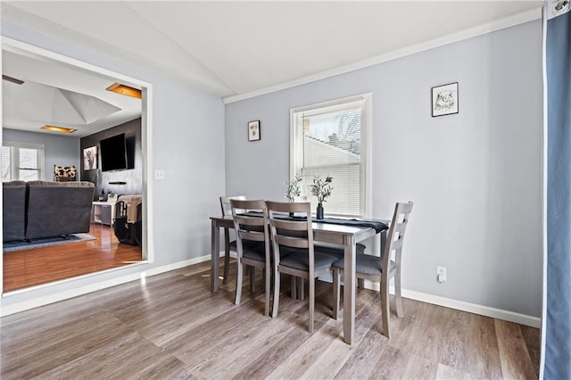 dining space featuring baseboards, lofted ceiling, and wood finished floors