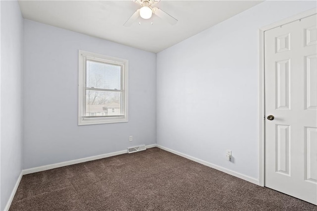 unfurnished room featuring visible vents, a ceiling fan, baseboards, and dark colored carpet