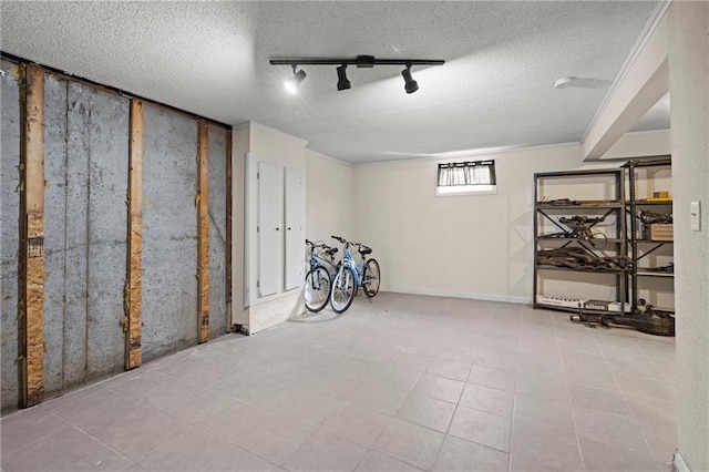 below grade area featuring a textured ceiling, ornamental molding, and track lighting