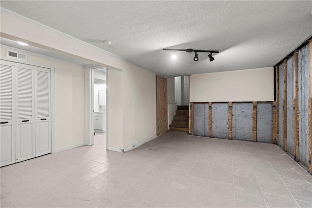 finished below grade area with stairway, baseboards, visible vents, a textured ceiling, and crown molding